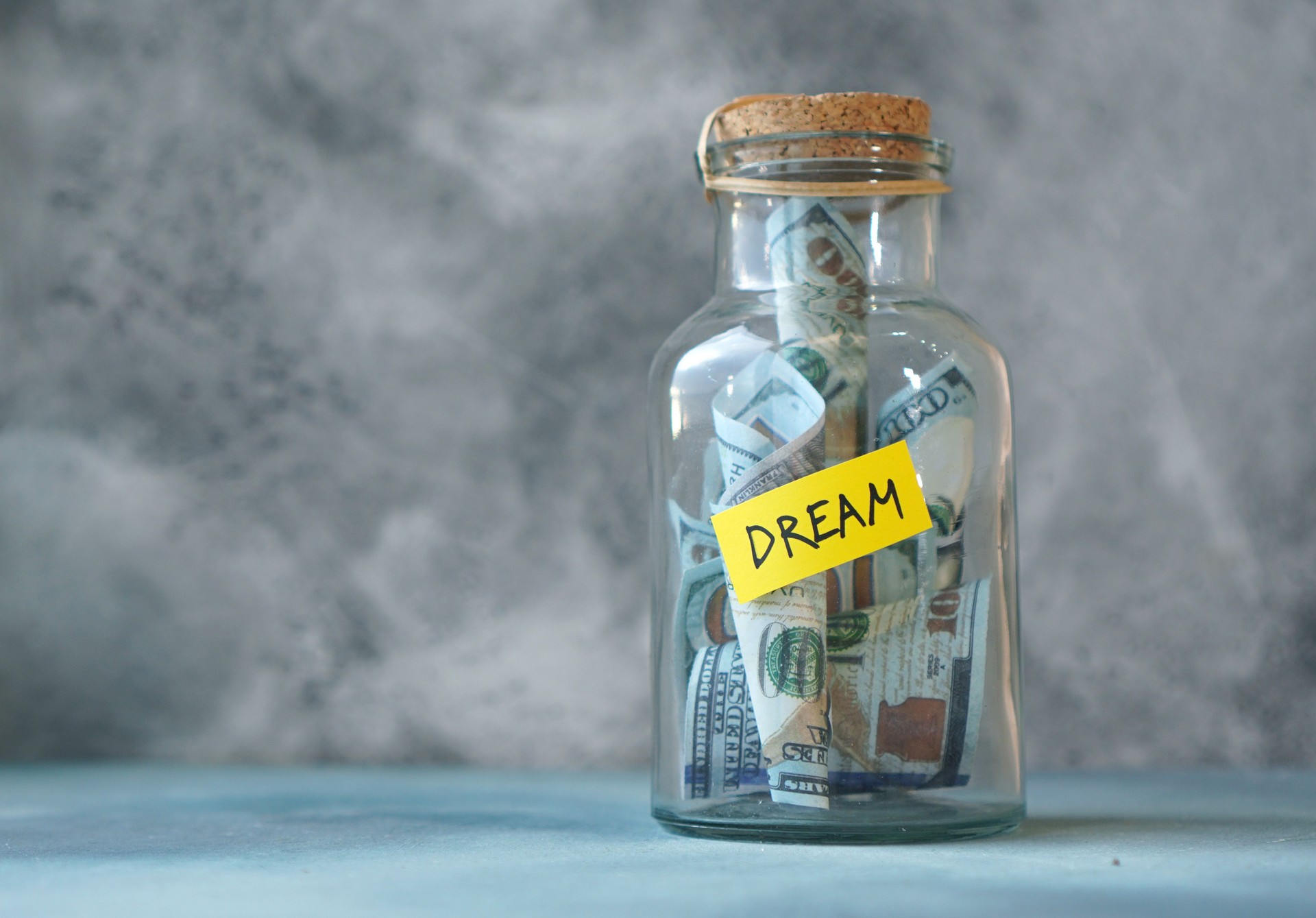 Money for a dream concept with glass jar labeled Dream filled with money.